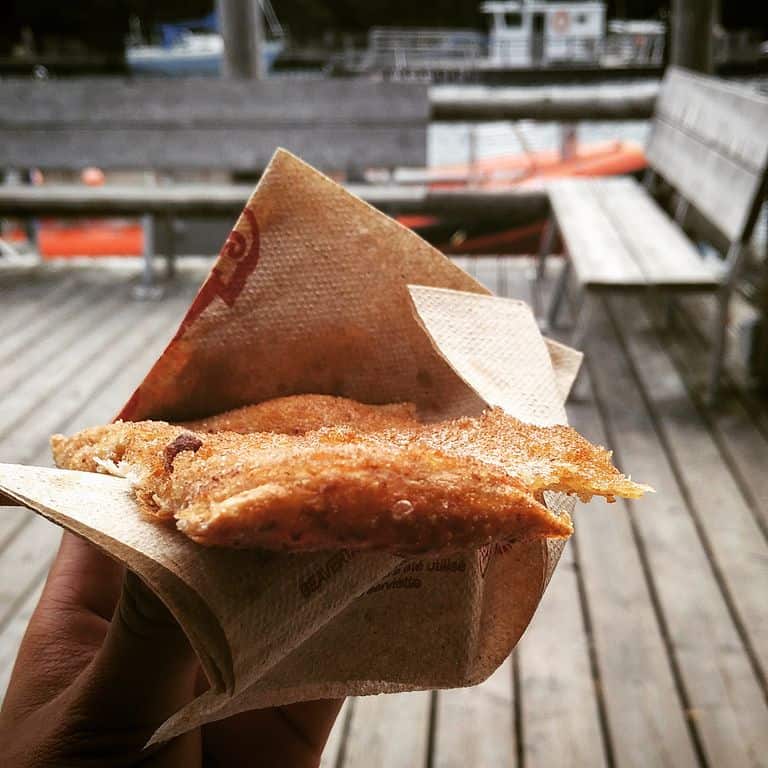 A cinnamon and sugar-topped pastry wrapped in a napkin, held by a happy diner.