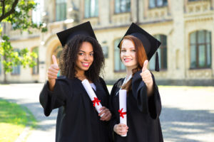 Two female graduates giving thumbs up