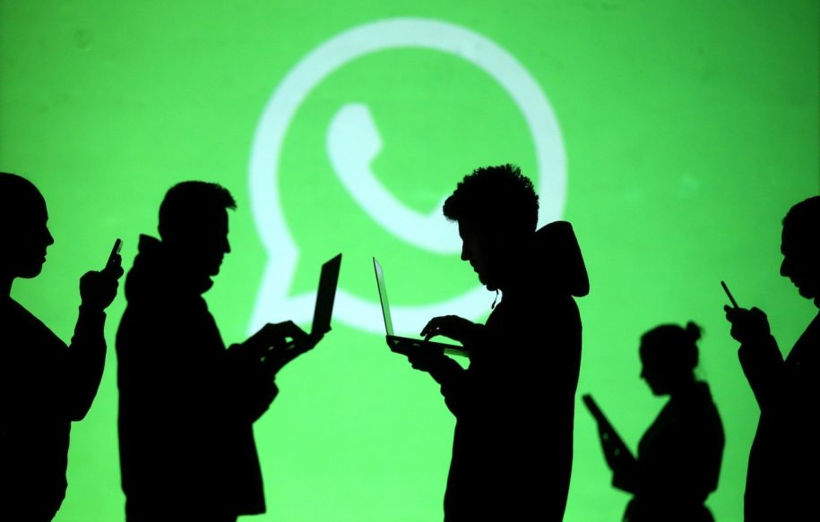 Silhouette of people on laptops and phones against WhatsApp logo