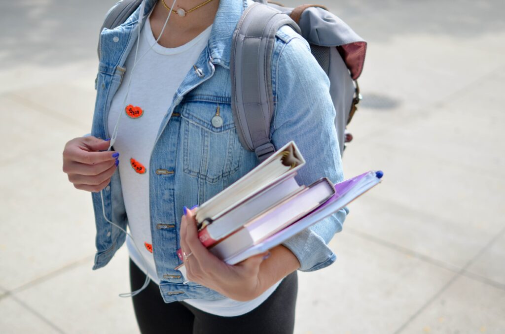 Woman wearing backpack and carrying books