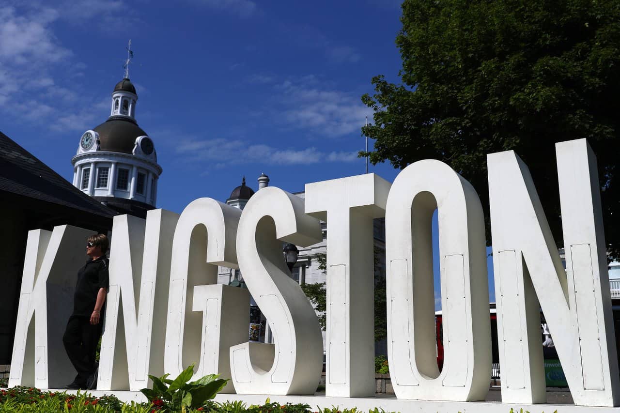 Photograph of person standing in front of Kingston sign