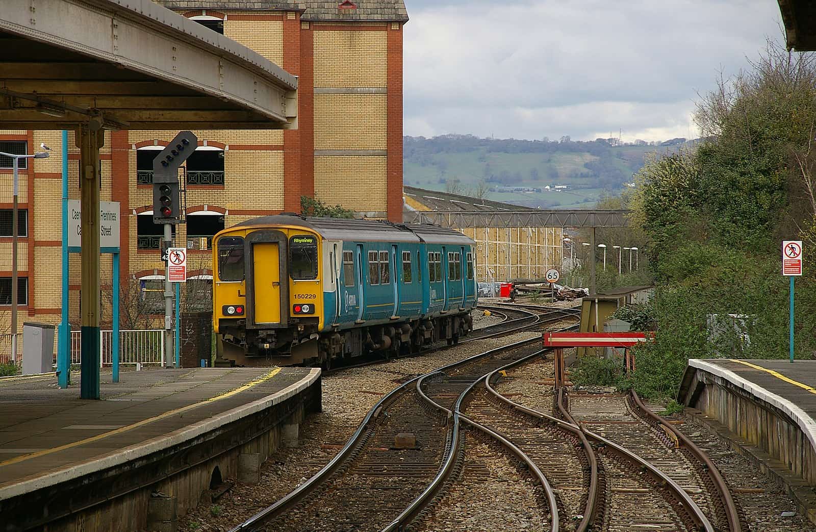 A photograph looking down the platform of Cardiff Queen Street railway station at a departing train.