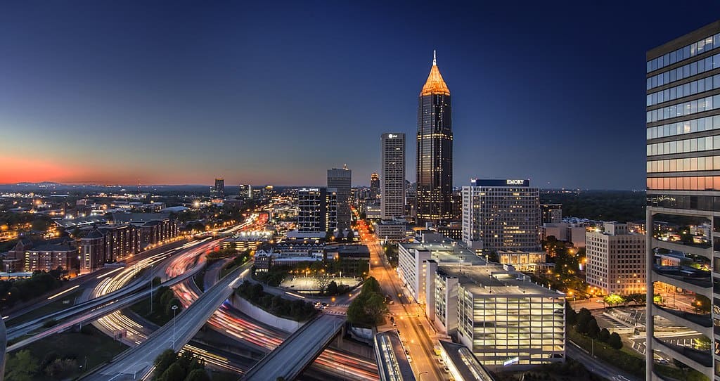 Midtown Atlanta's skyline at twilight; orange light streams on a series of elevated highways, with tall office and apartment buildings on either side.