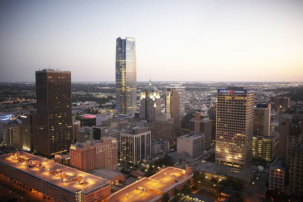 The Oklahoma City skyline at twilight, in the main business district (tall buildings lit up, with the city proper beyond.)