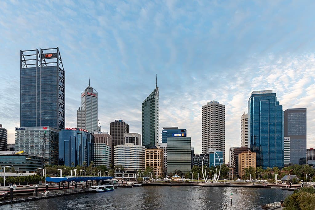 The cityscape of Perth, Australia: a waterfront with several tall skyscrapers and large art installations on the shore.
