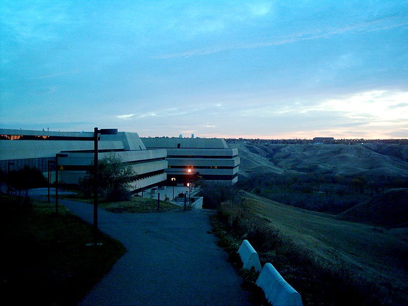 University of Lethbridge campus (low-slung concrete and glass buildings against an early-morning blue prairie sky.)