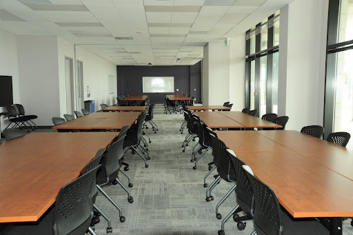 A photograph of a classroom at Niagara University in Ontario - a long, bright room with wooden tables and swivelly office chairs.