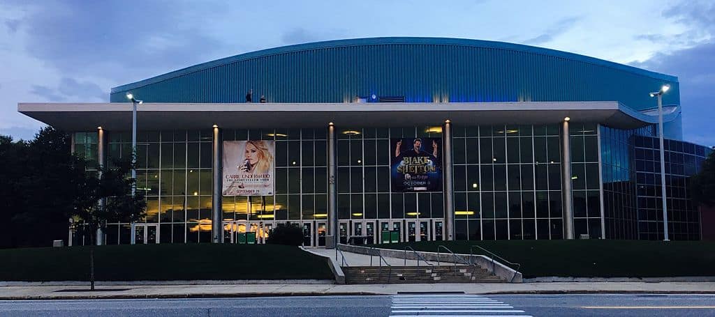 A large, modern arena building with country music posters hanging from its front columns (SNHU Arena)
