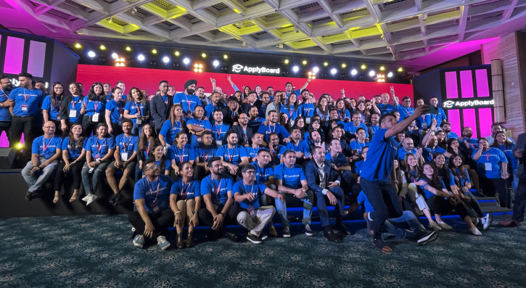 A high-quality photo of the ApplyBoard team at TRW 2022, featuring many dozens of peopleÂ all wearing blue ApplyBoard t-shirts.