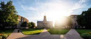 A photograph of the University of Iowa's main campus with one student walking.