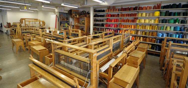 A classroom at OCAD University, filled with spools of yarn, thread, and yards of fabric.