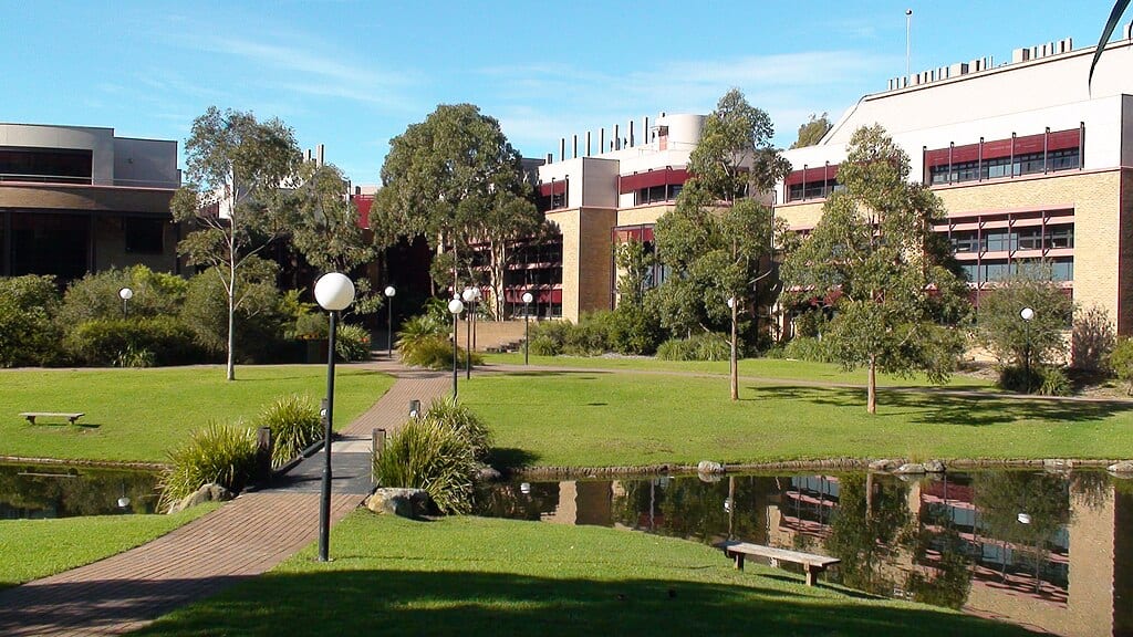 Mid-20th-century brick buildings sit on a green university quad at the University of Wollongong, Australia.