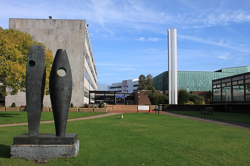 Part of the University of Southampton's Highfield campus: a modern art sculpture in the middle of a grassy quad, surrounded by mid-20th century concrete and glass buildings. The campus is quiet, likely class is not in session.