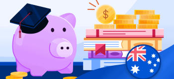 A mauve piggy bank with a graduation cap sits beside a stack of books and coins.