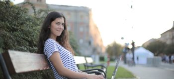 Girl working on laptop on park bench